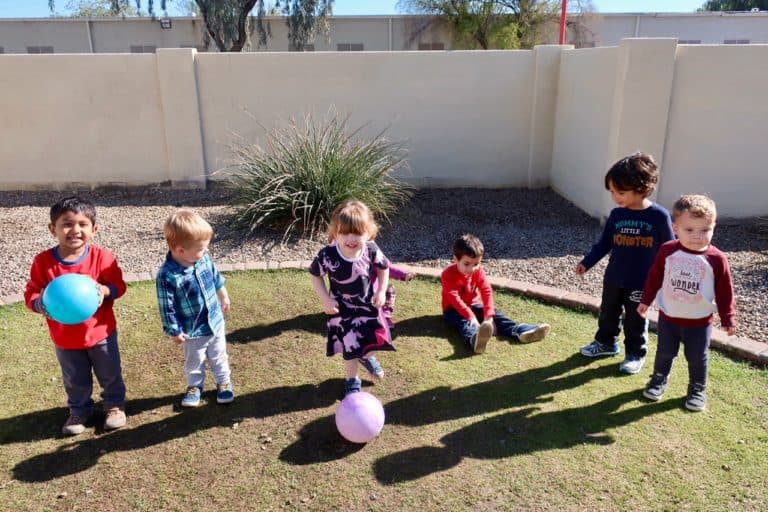 Five children playing with a ball outdoors.