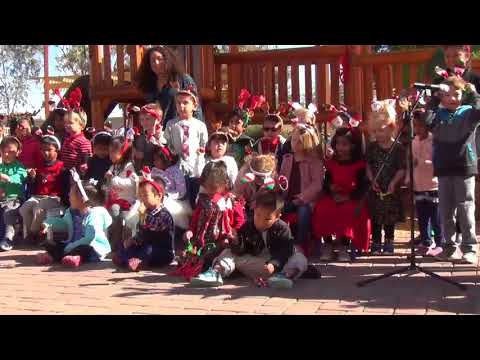 Children in red and white singing on stage.