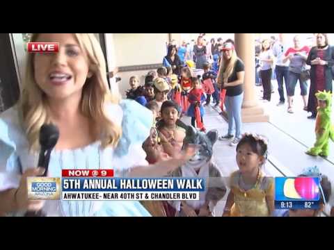Woman in blue dress reporting on Halloween walk.