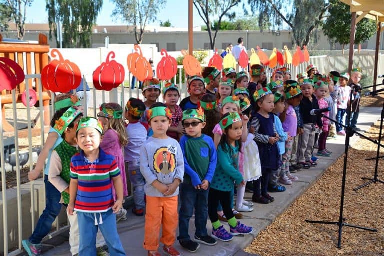 Children in pumpkin hats perform at school.