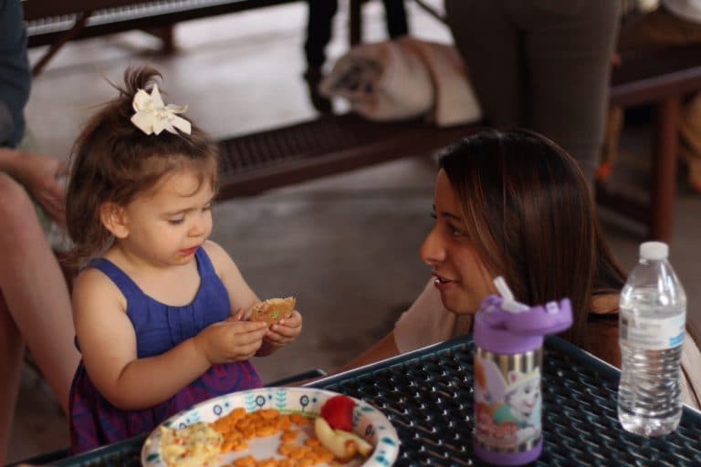 Young girl eating snack with woman.