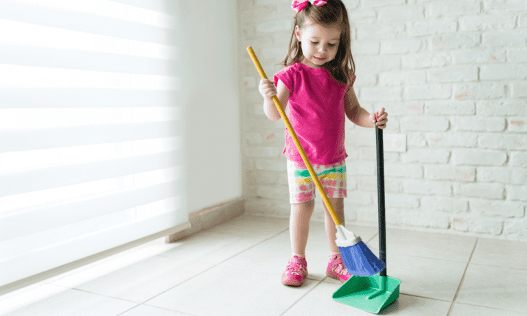 Little girl sweeping floor with broom.