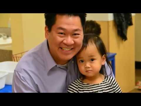Man smiling with young girl in stripes.