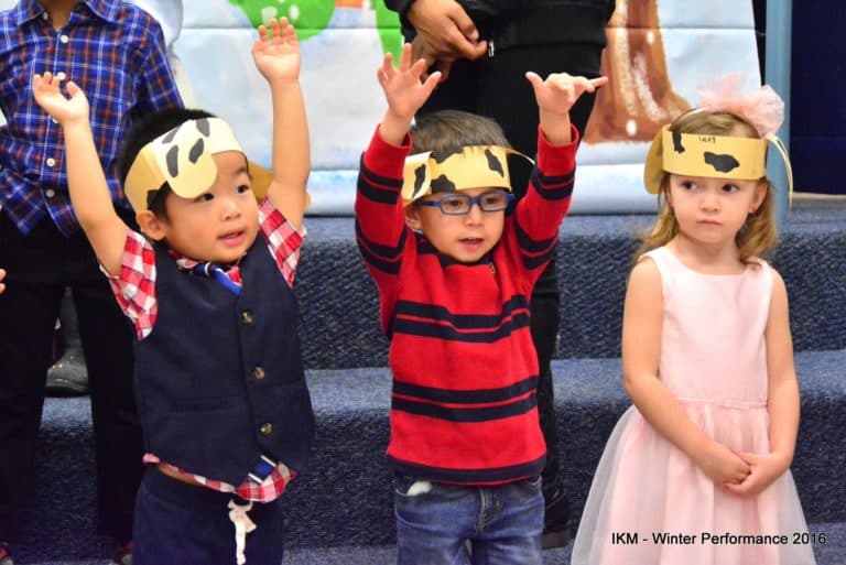 Three children in festive costumes performing.