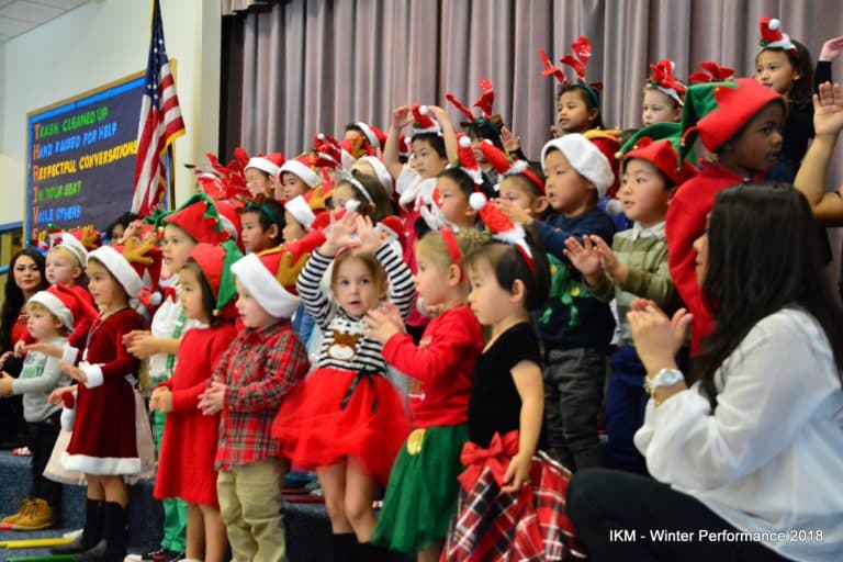 Children in Santa hats singing at a school event.