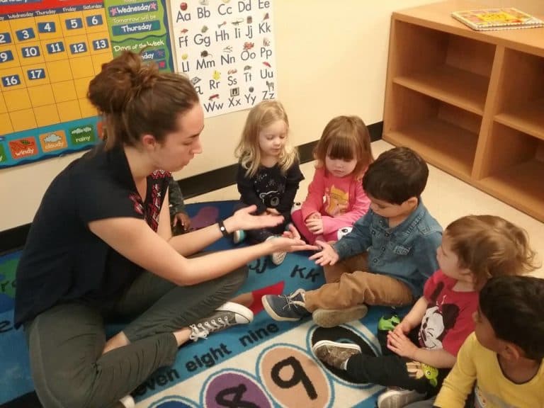 Teacher and children learning numbers on rug.