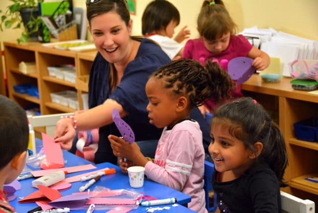 Teacher and children crafting with paper.