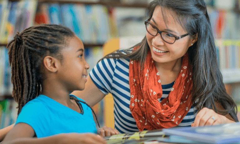 Teacher and student reading together in library.