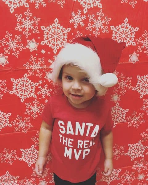 Young child wearing a Santa shirt.
