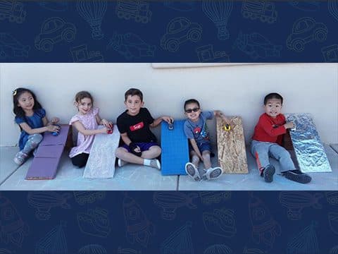 Five children sitting on colorful ramps.