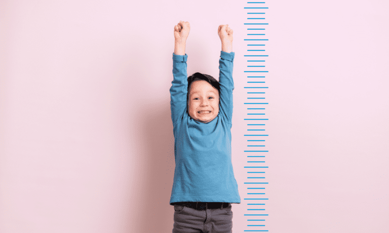 Happy boy measuring height chart.