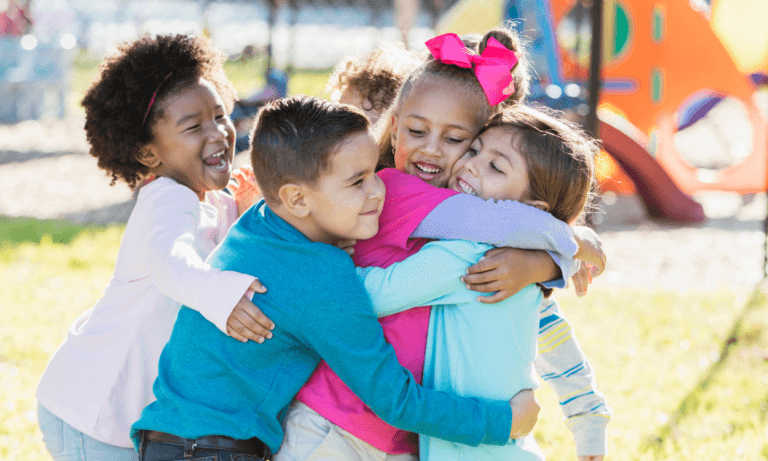 Happy children hugging outdoors.